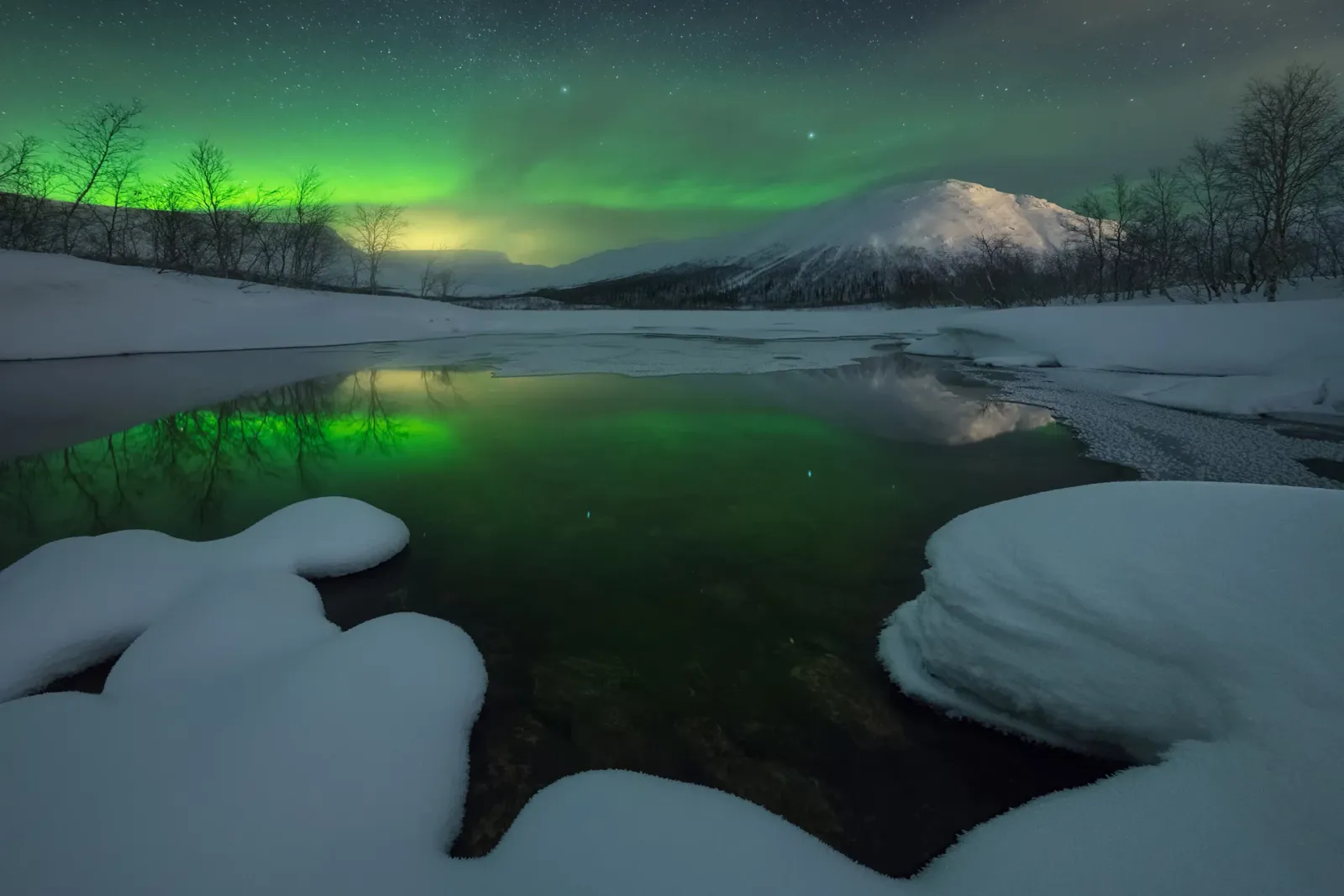 Northern lights over a snowy landscape in Lapland