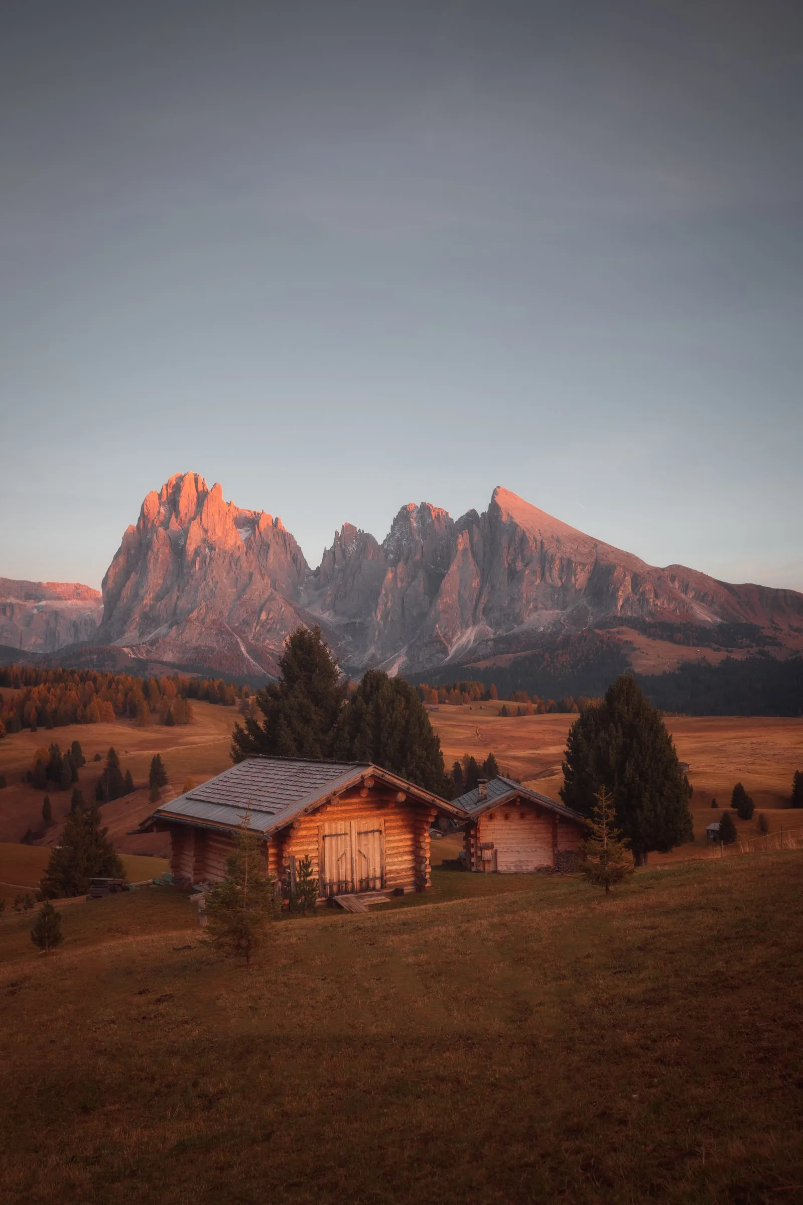El Sassolungo iluminado al atardecer sobre cabañas de madera