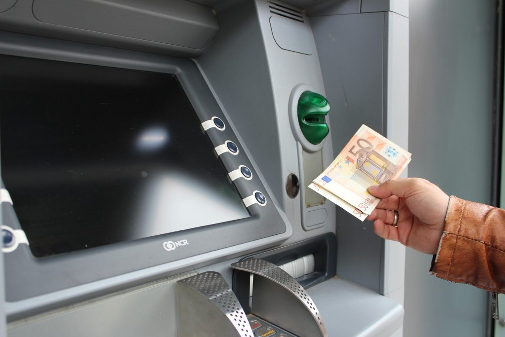Detalle de una persona que usa un cajero automático para sacar efectivo en euros