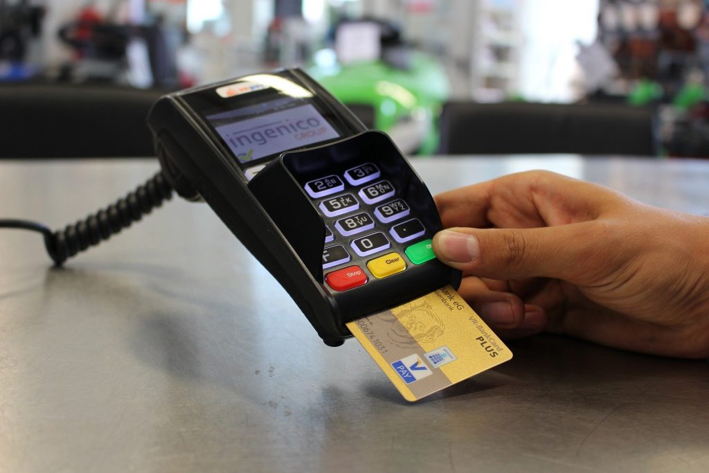 persona que usa una tarjeta de débito de viaje en la tienda durante un viaje