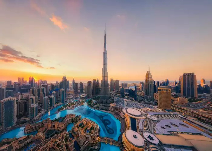 Vista aérea de Burj Khalifa en el horizonte y la fuente del centro de Dubái, Emiratos Árabes Unidos o EAU. Distrito financiero y zona de negocios en ciudad urbana inteligente. Rascacielos y edificios altos al atardecer.
