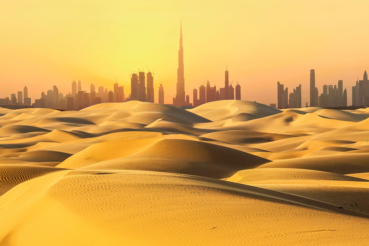 Dubai cityscape in desert at sunset.